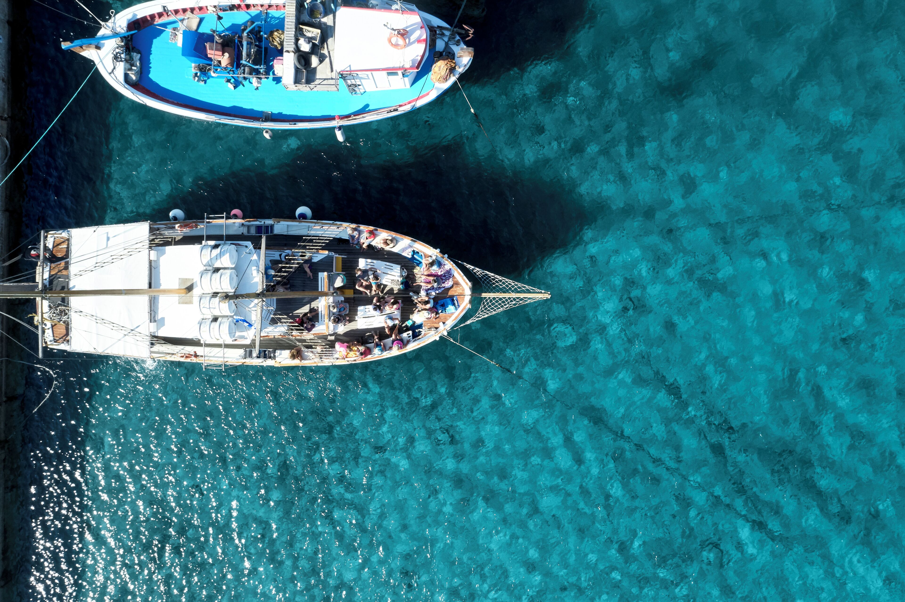 Two boats docked in clear turquoise water.