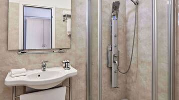 Un baño moderno con ducha envuelta en cristal, un lavabo con espejo y un perchero para toallas.