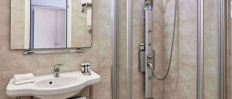 A modern bathroom with a glass-enclosed shower, a sink with a mirror above it, and a towel rack.