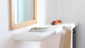 A white bedside table with a book, a bowl of fruit, and a mirror. - Lagos Mare Hotel (Naxos)