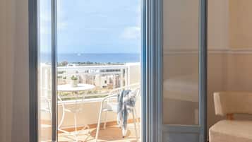 Una habitación con vista al mar, un balcón con mesa y sillas, y una cama.