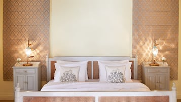 A bedroom with a bed, two nightstands, and patterned wallpaper.