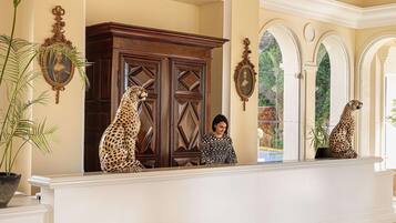 A reception area with a wooden cabinet, two leopard statues, and a woman standing in front.
