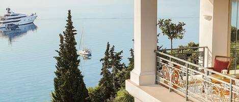 A balcony with a view of a calm lake, a yacht, and a sailboat.