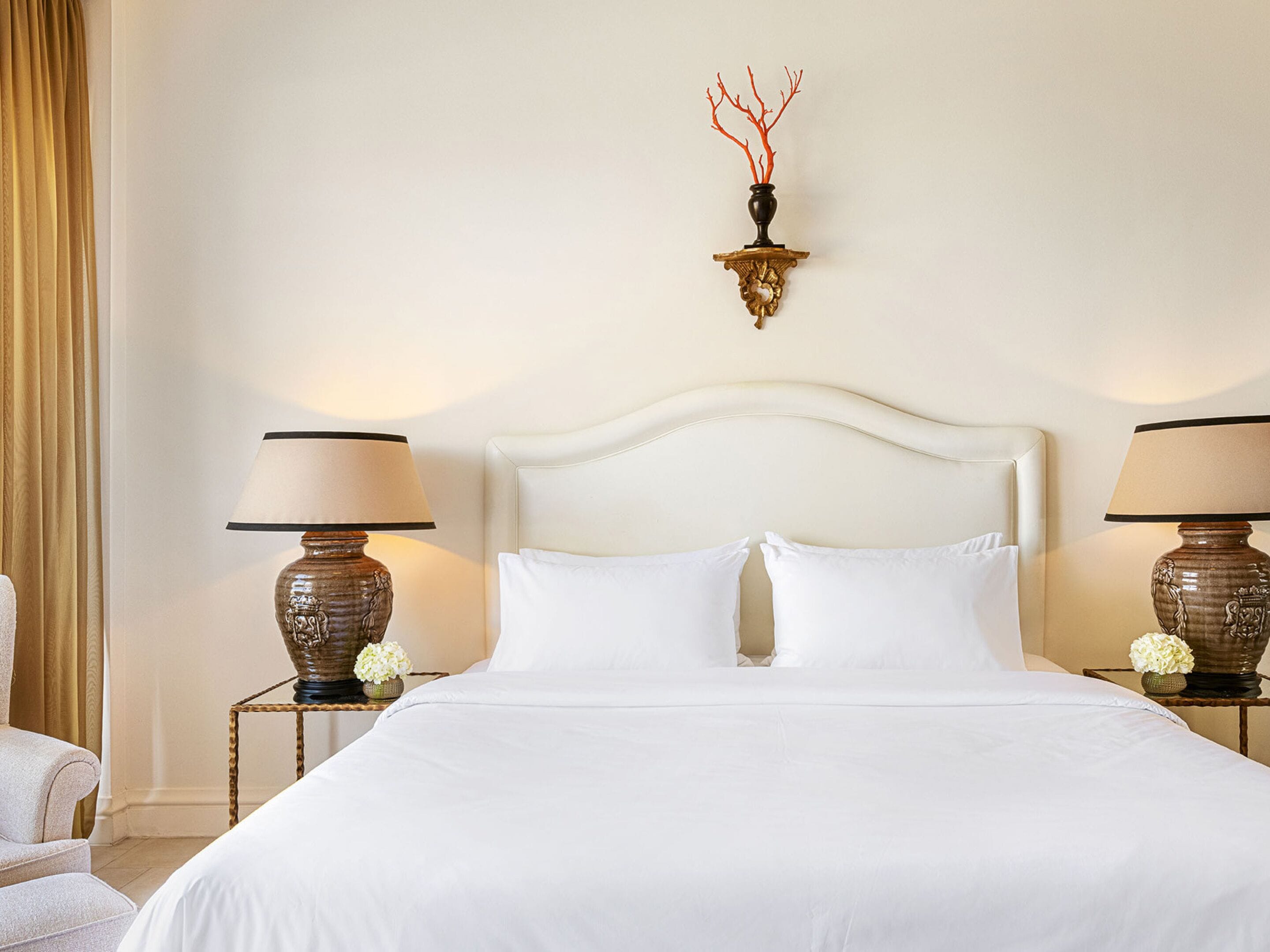 A hotel room with a large bed, two bedside tables with lamps, and a wall-mounted light fixture.