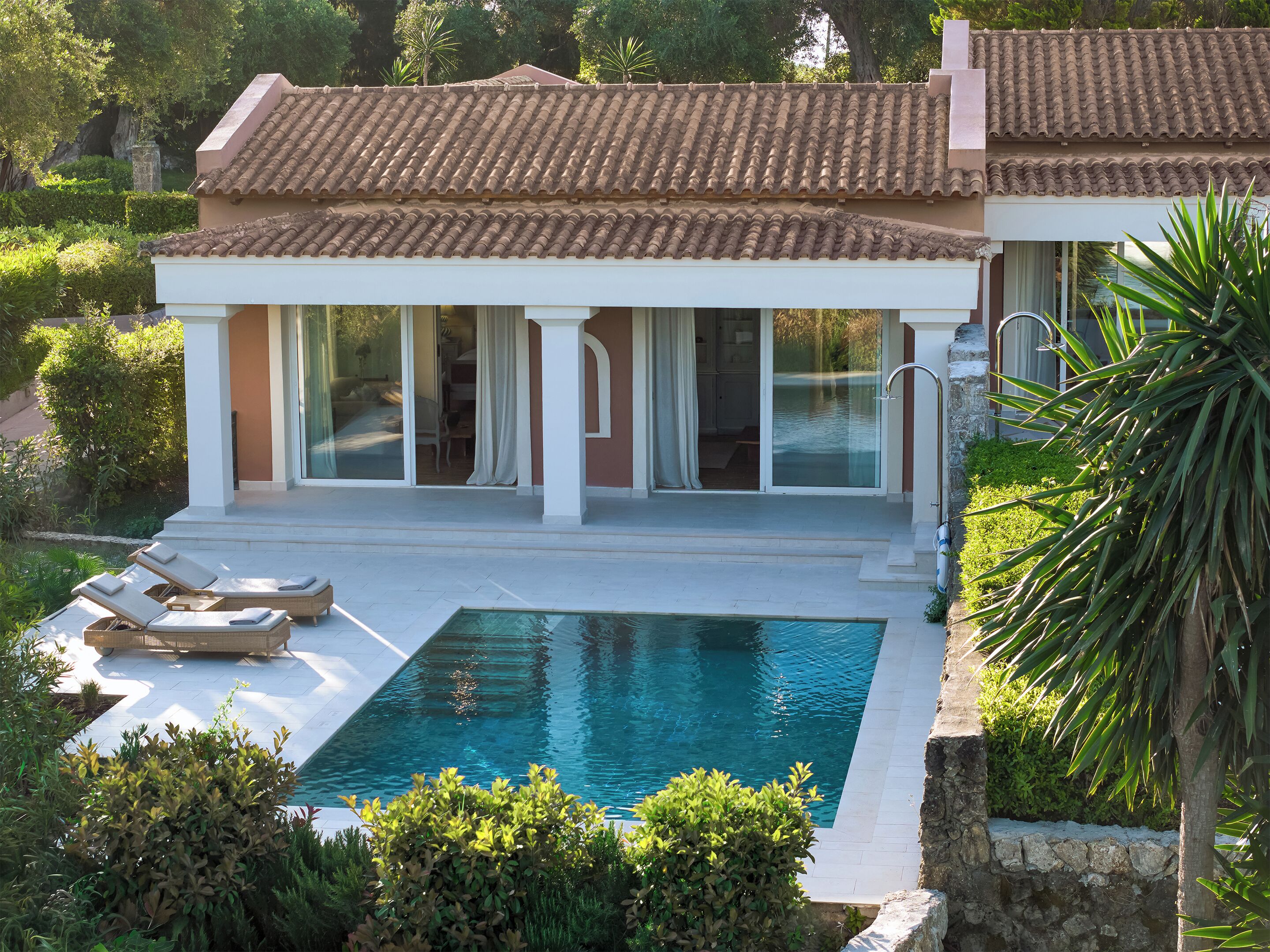 Una villa con piscina, tumbonas y jardín.