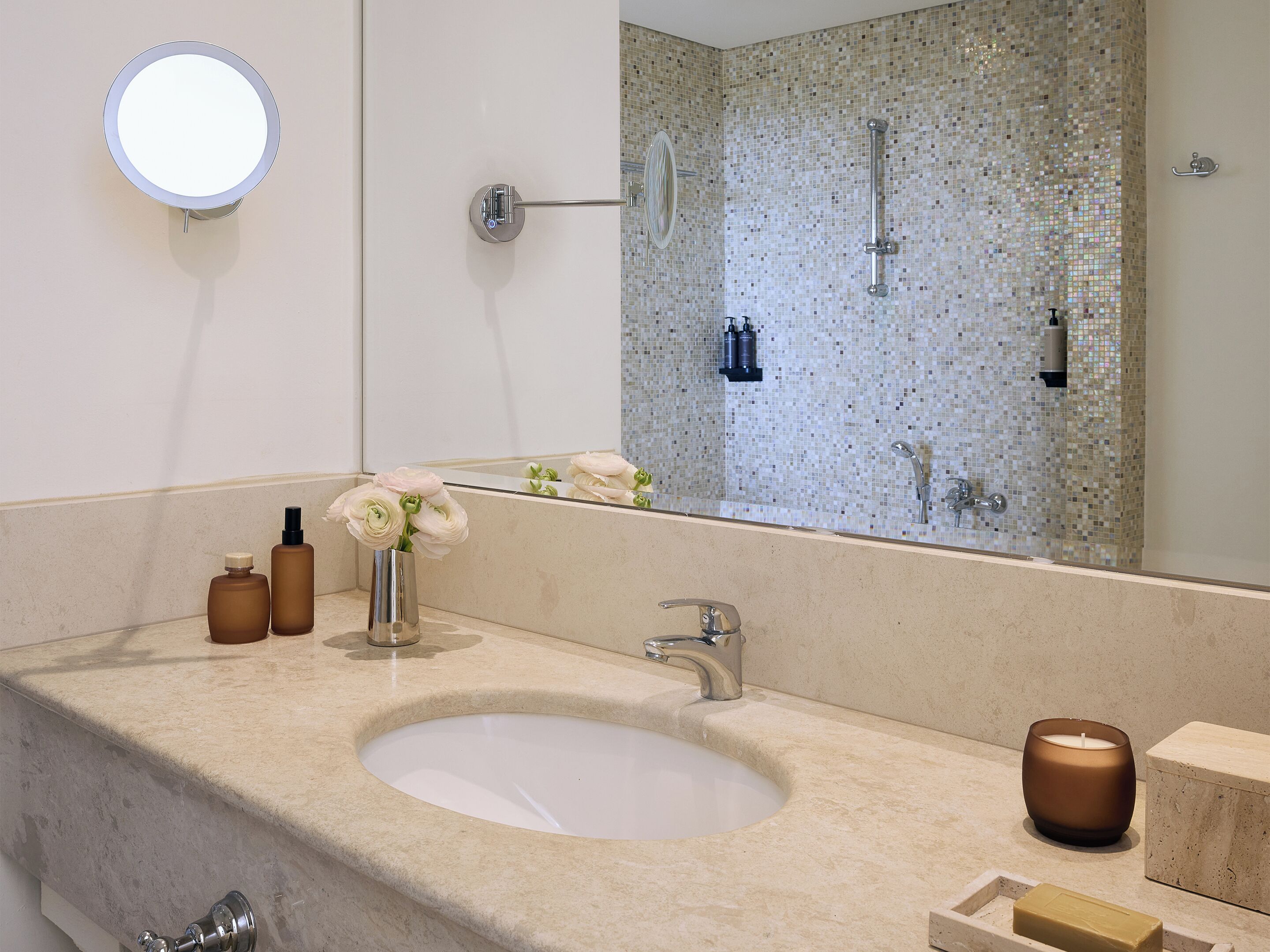 Un baño con un espejo redondo, un lavamanos y una zona de ducha.