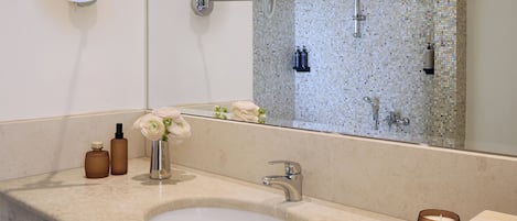 Un baño con un espejo redondo, un lavamanos y una zona de ducha.