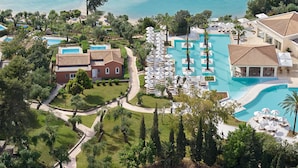 Vista aérea de un resort con múltiples piscinas, exuberante vegetación y propiedades frente a la playa.