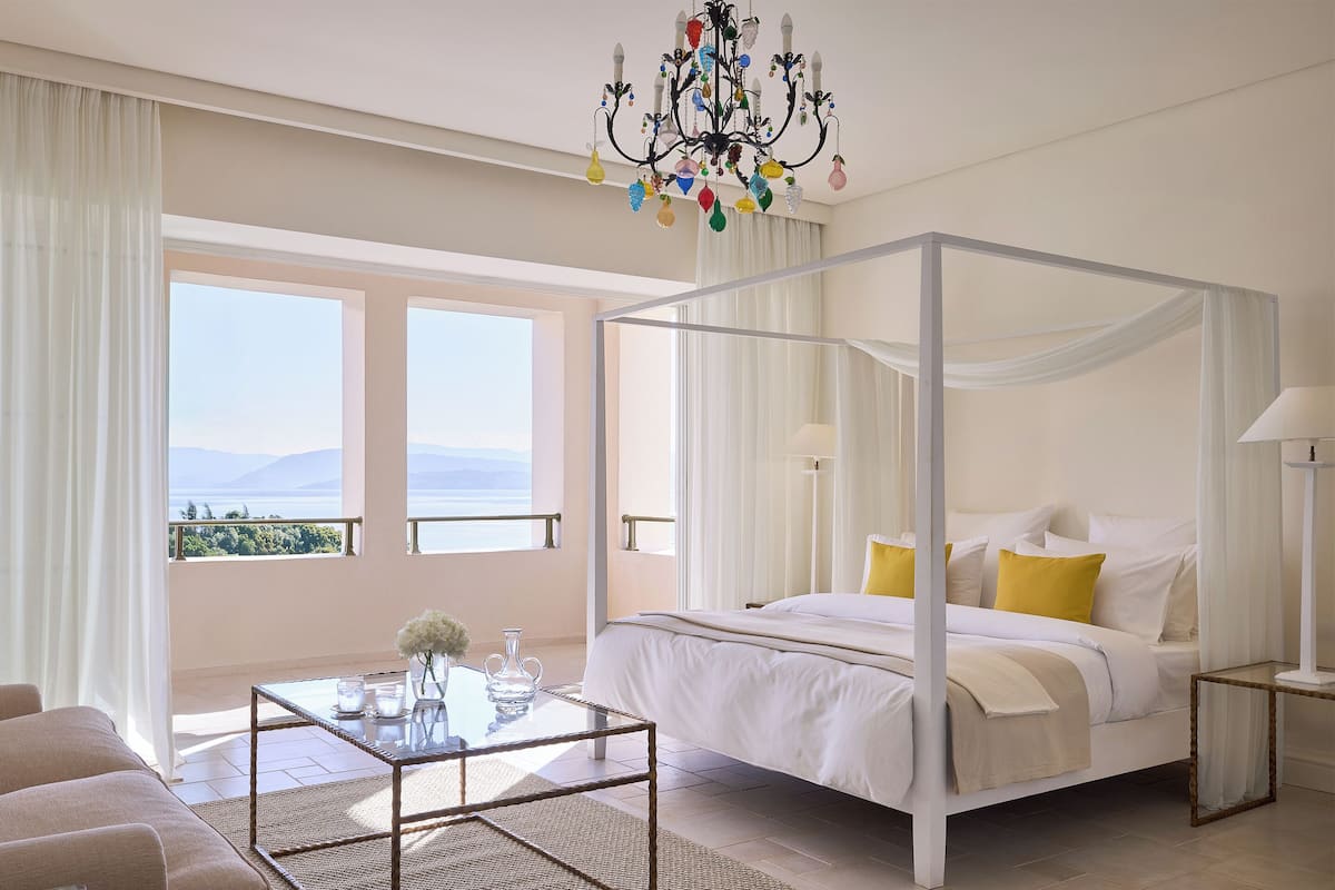 Quarto espaçoso com cama de dossel, mesa de centro de vidro e vista para o exterior.