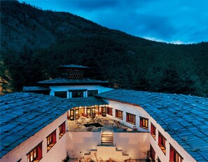 A traditional building with a courtyard, a staircase leading to the upper level, and a view of a forested mountain in the background. - COMO Uma Paro (Paro)