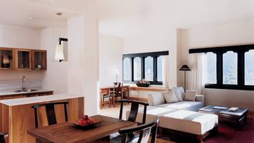 A modern living room with a sofa, coffee table, and dining area with a wooden table and chairs.