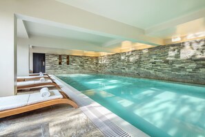 Una piscina techada, una piscina al aire libre, sombrillas