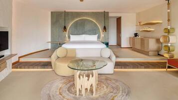 A modern hotel room with a large bed, a glass coffee table, and a unique wall design.