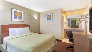 Una habitación de hotel con una cama, un escritorio y una silla. Hay dos cuadros en la pared.