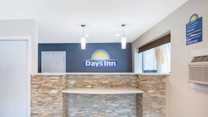 Vestíbulo de un Days Inn con una pared decorada con piedra, un mostrador de recepción y un cartel que indica los horarios de registro.