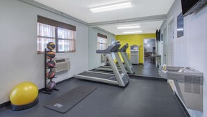 Un gimnasio con cintas de correr, pelotas de ejercicio y una colchoneta de yoga.