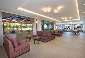 Amplia sala de estar con sofás, mesas y vistas al exterior.