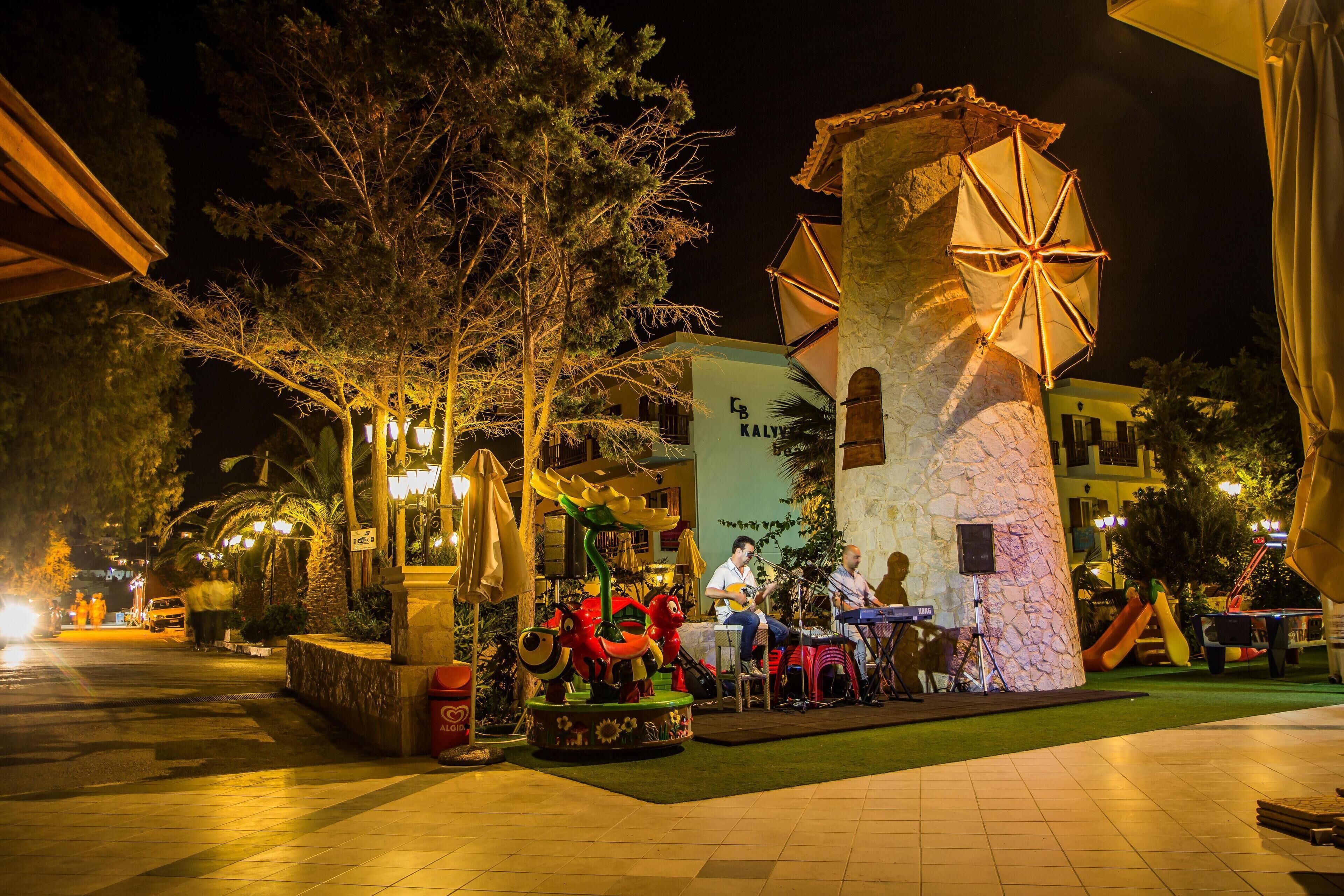 A courtyard with a stone tower, outdoor seating, and a stage for live music.
