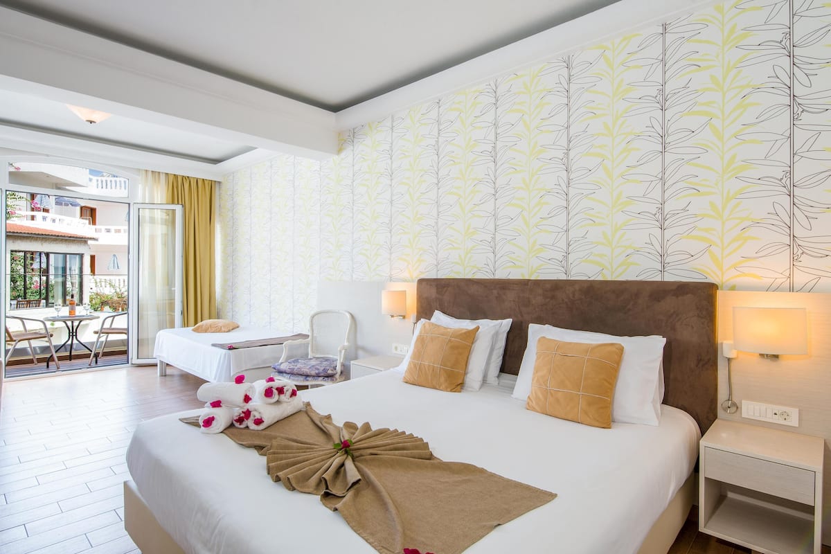 A hotel room with a large bed, a desk, and a balcony.