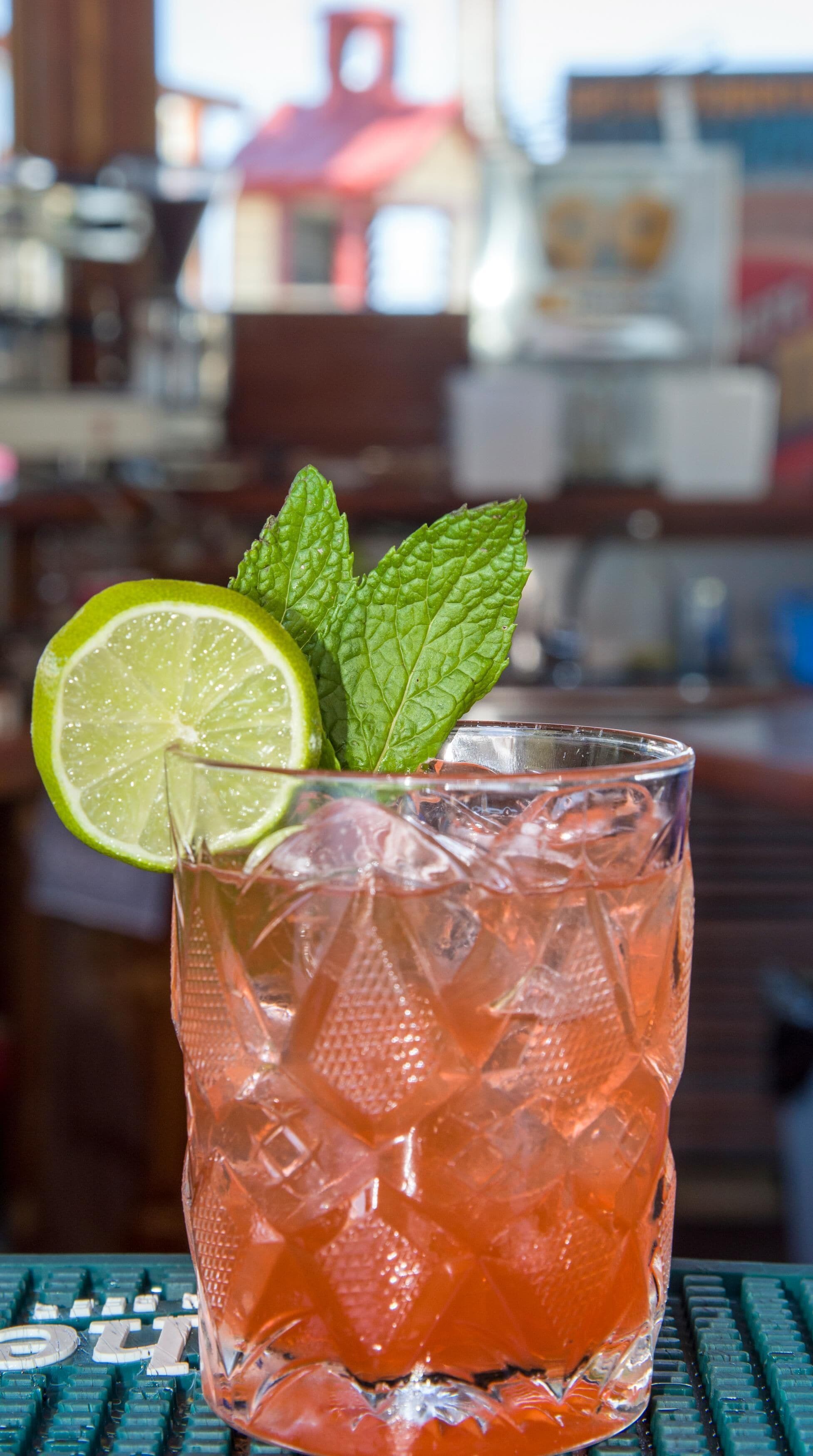 Un verre contenant une tranche de citron vert et quelques feuilles de menthe, posé sur le comptoir d’un bar.