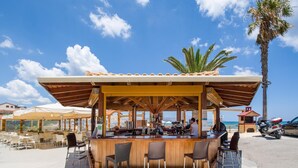 Zona de bar al aire libre con estructura de madera, taburetes y sombrillas.