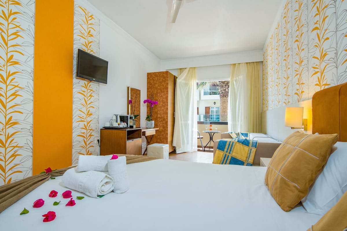 A hotel room with a bed, a desk, a TV, and a view of the outside.