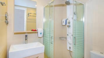 Une salle de bain moderne avec une douche à parois de verre, un lavabo blanc et un miroir au-dessus.