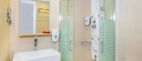 A modern bathroom with a glass-enclosed shower, a white sink, and a mirror above it.