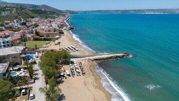 Un pueblo costero con una playa, un rompeolas rocoso y una zona de piscina.