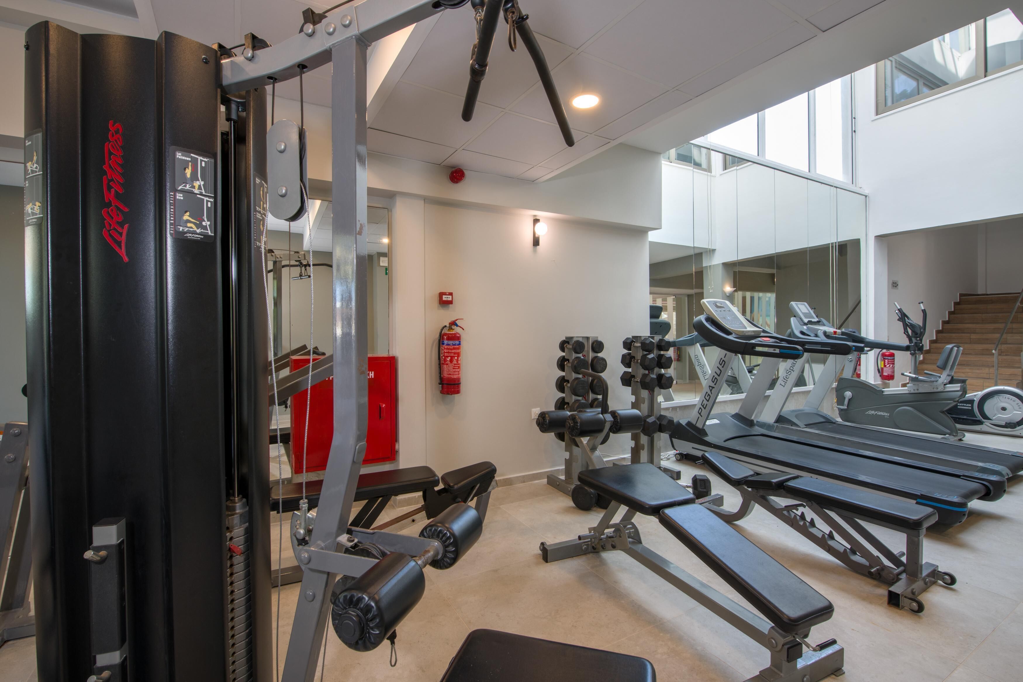Un gimnasio con máquinas de pesas, cintas de correr y mancuernas.