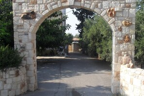An arched stone gateway leading to a street with trees and buildings in the background.