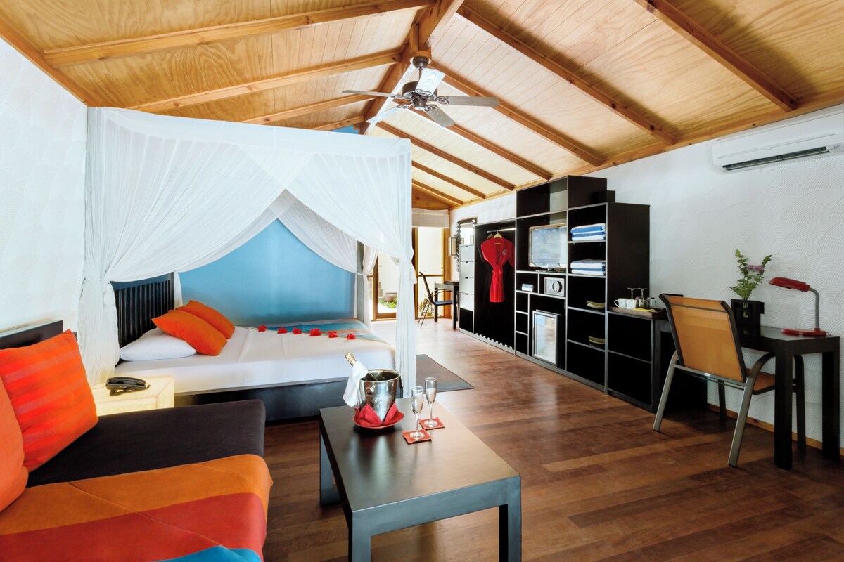 Une pièce comprenant un lit, un canapé, une table avec un seau et des verres, un bureau avec une chaise et une armoire.