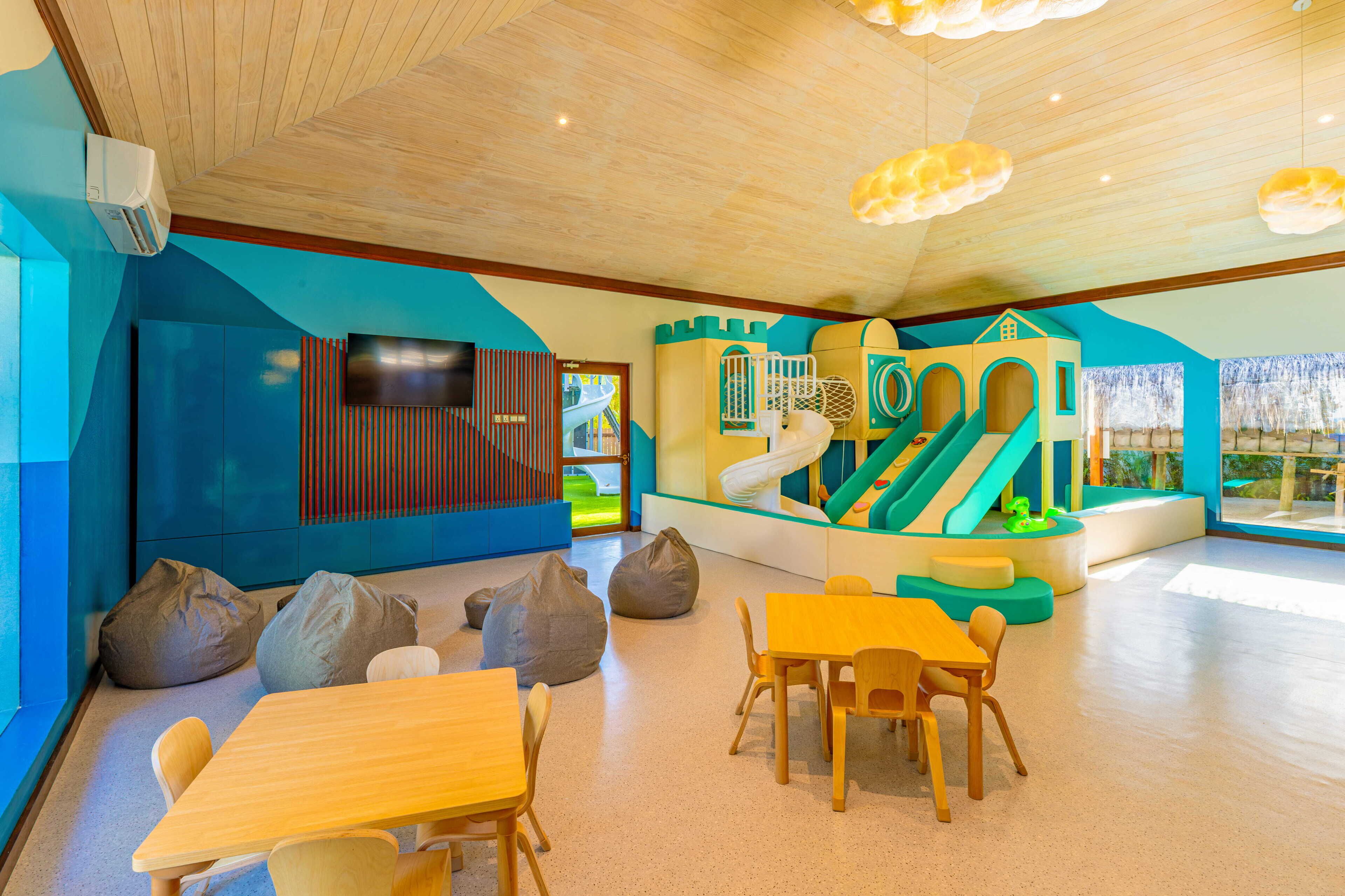 Zona de juegos infantiles con tobogán, estructuras para escalar y asientos.