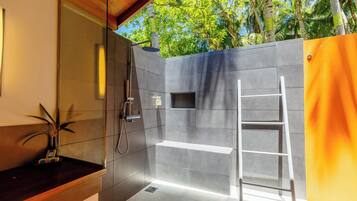 Enjoy a refreshing shower experience with a glass-enclosed shower, handheld showerhead, and bench.