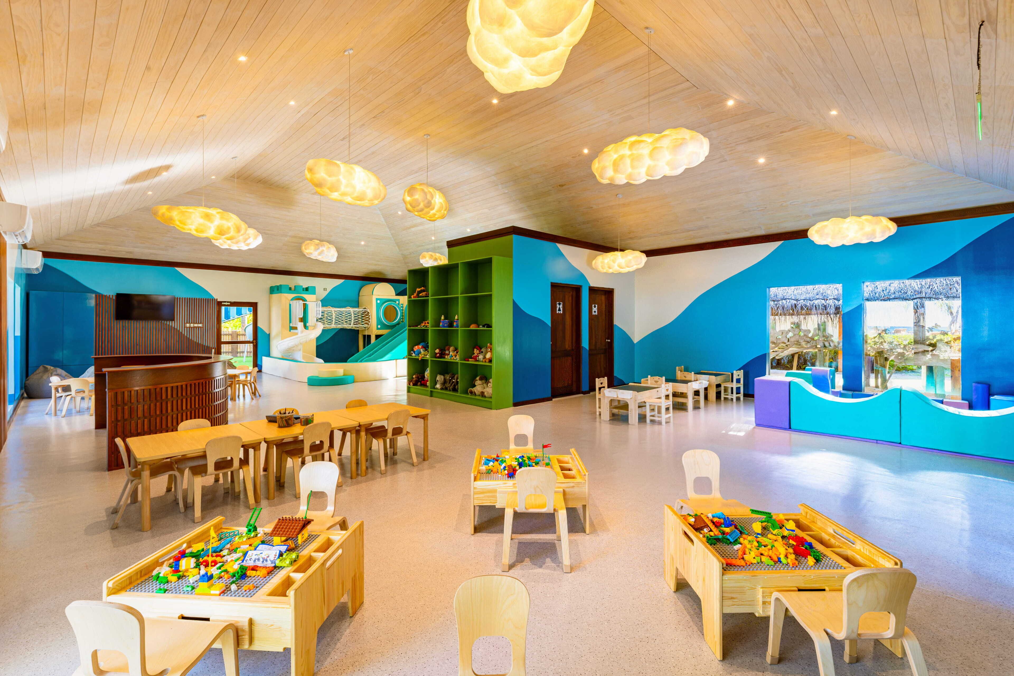 Ein Spielbereich für Kinder mit Tischen, Stühlen und Spielgeräten.