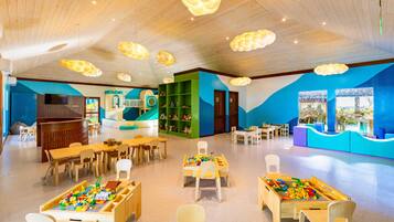 Ein Spielbereich für Kinder mit Tischen, Stühlen und Spielgeräten.