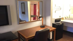 A hotel room with a wooden desk, a black office chair, a small black desk, a microwave, a sink, and a mirror. - Sunshine Motel (Fife)