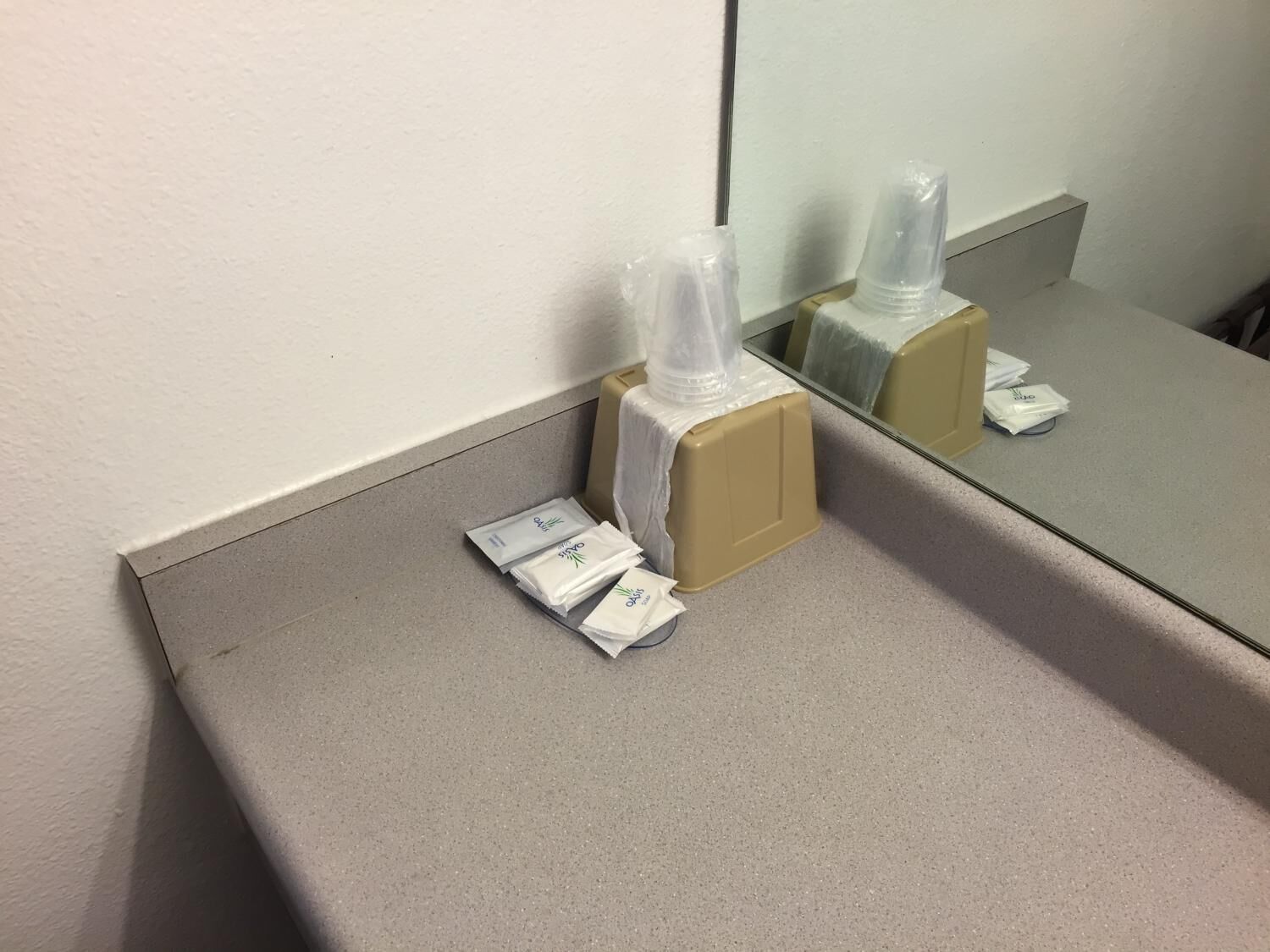 Une salle de bain équipée d’un miroir, d’un distributeur de serviettes et d’un distributeur de savon, le tout placé sur un comptoir.