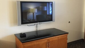 A flat-screen TV mounted on a wall above a wooden cabinet with a black top. - Sunshine Motel (Fife)