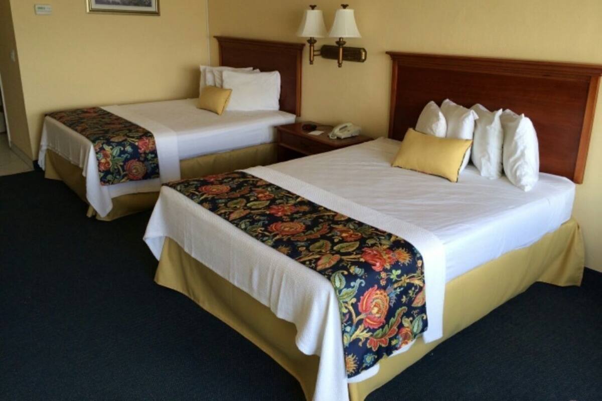 Two single beds with floral bedspreads, bedside lamps, and a painting on the wall.
