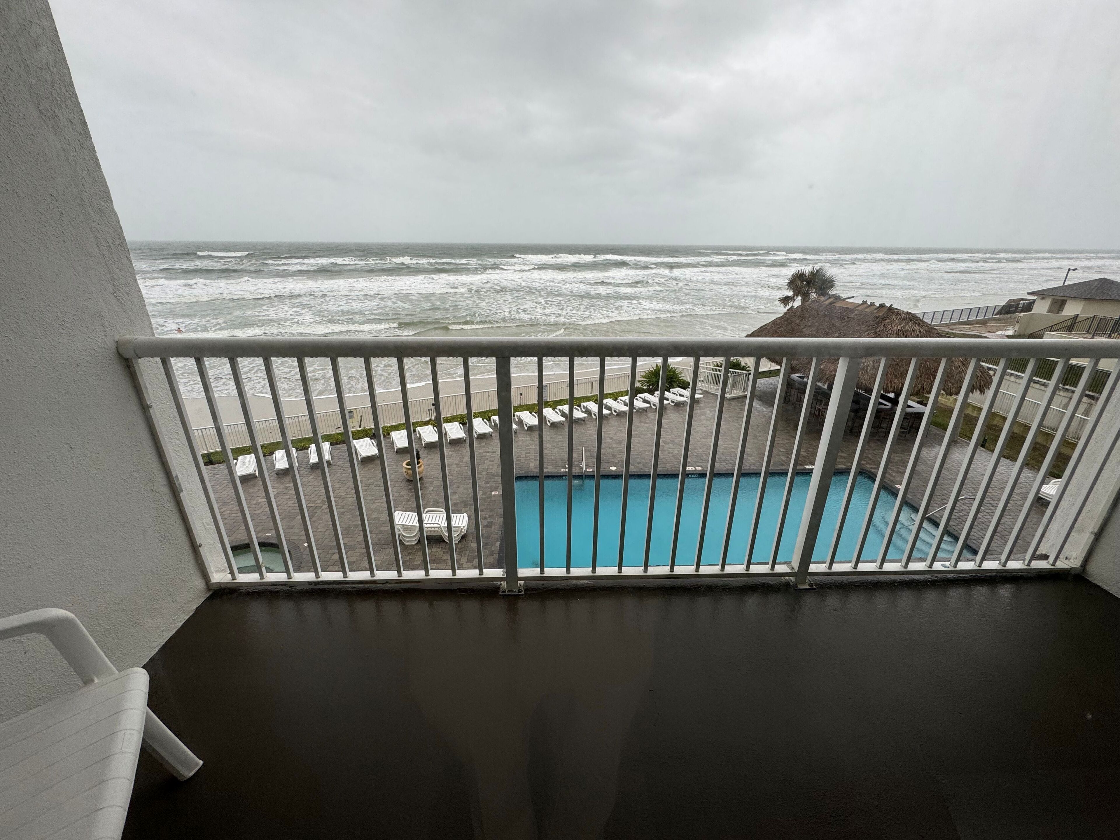 A balcony with a view of the ocean and a swimming pool.