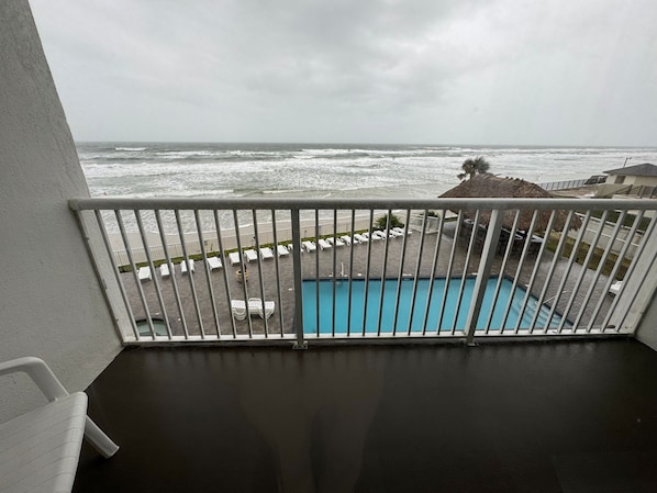 A balcony with a view of the ocean and a swimming pool.