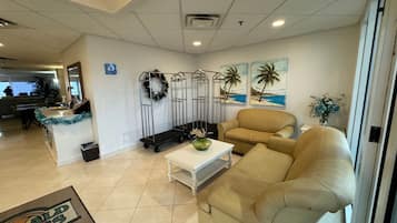 A hotel lobby with a reception desk, a beige sofa, a white coffee table, and a decorative wreath.