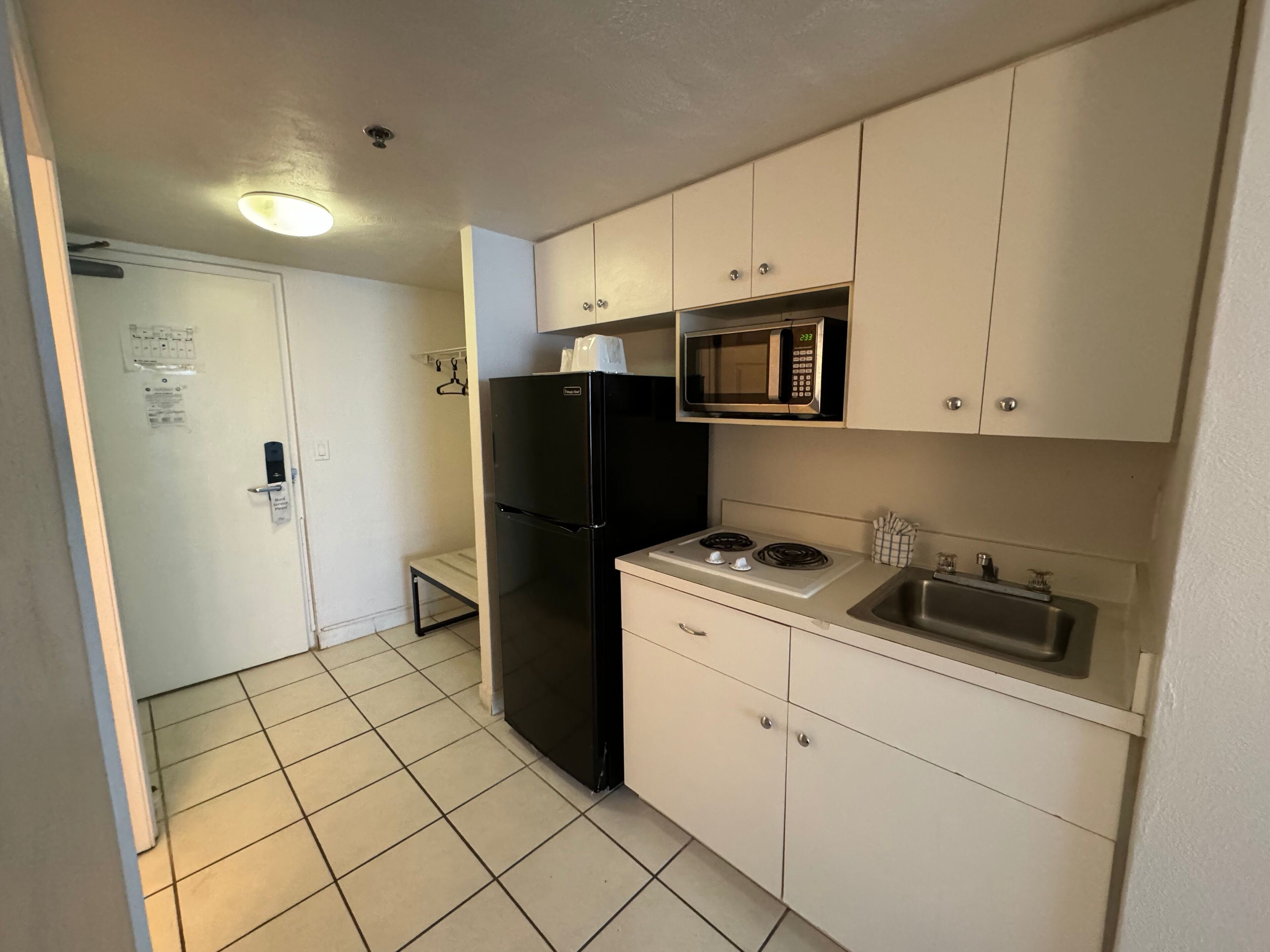 A compact kitchen with a refrigerator, microwave, stove, and sink.