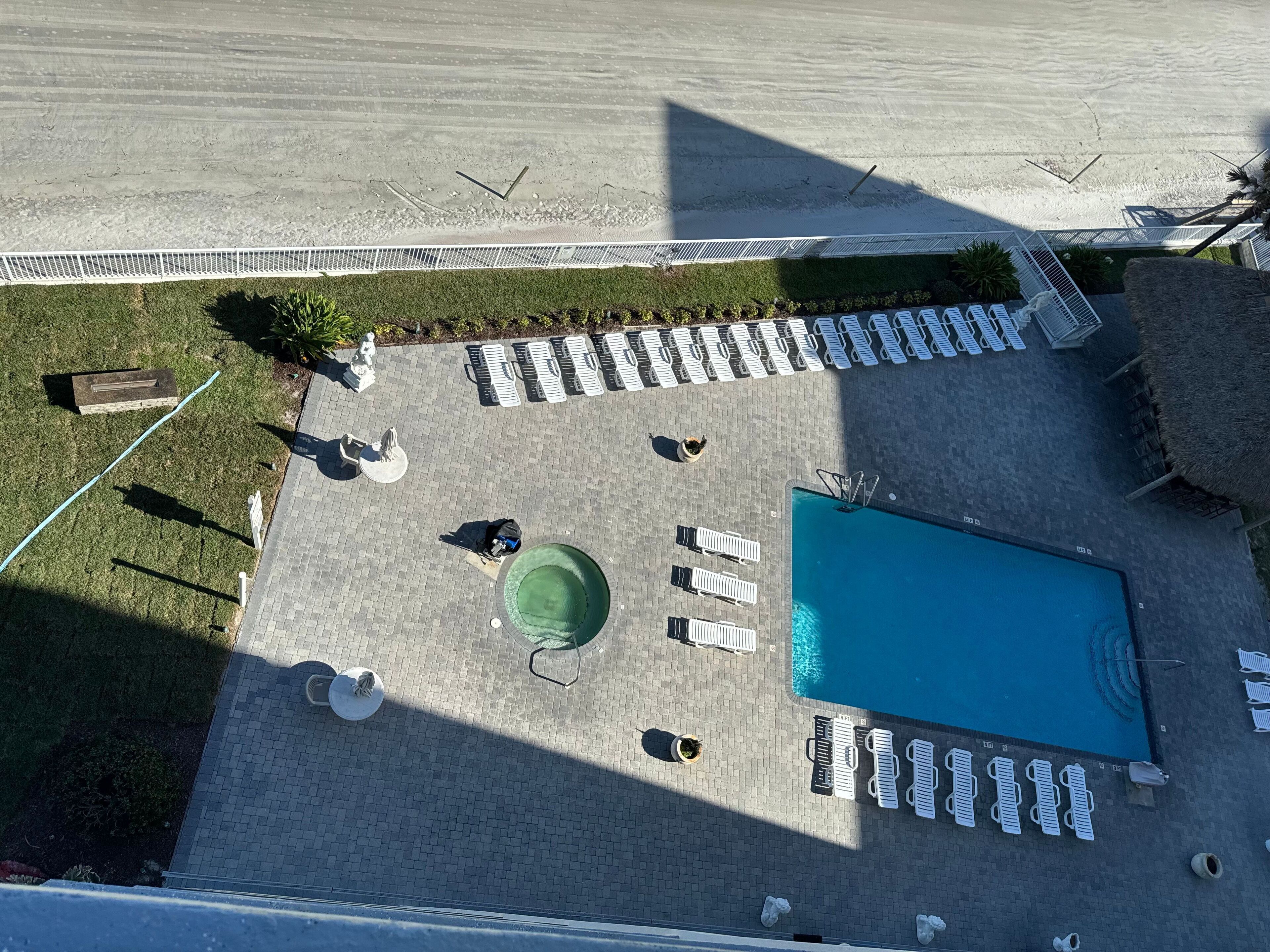 Luchtbeeld van een zwembad met een rechthoekig zwembad, meerdere ligbedden en een kleine ronde tafel.