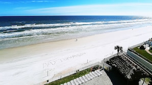 Una playa con cielo despejado, una orilla arenosa y un cartel que dice "DAYTONA BEACH".