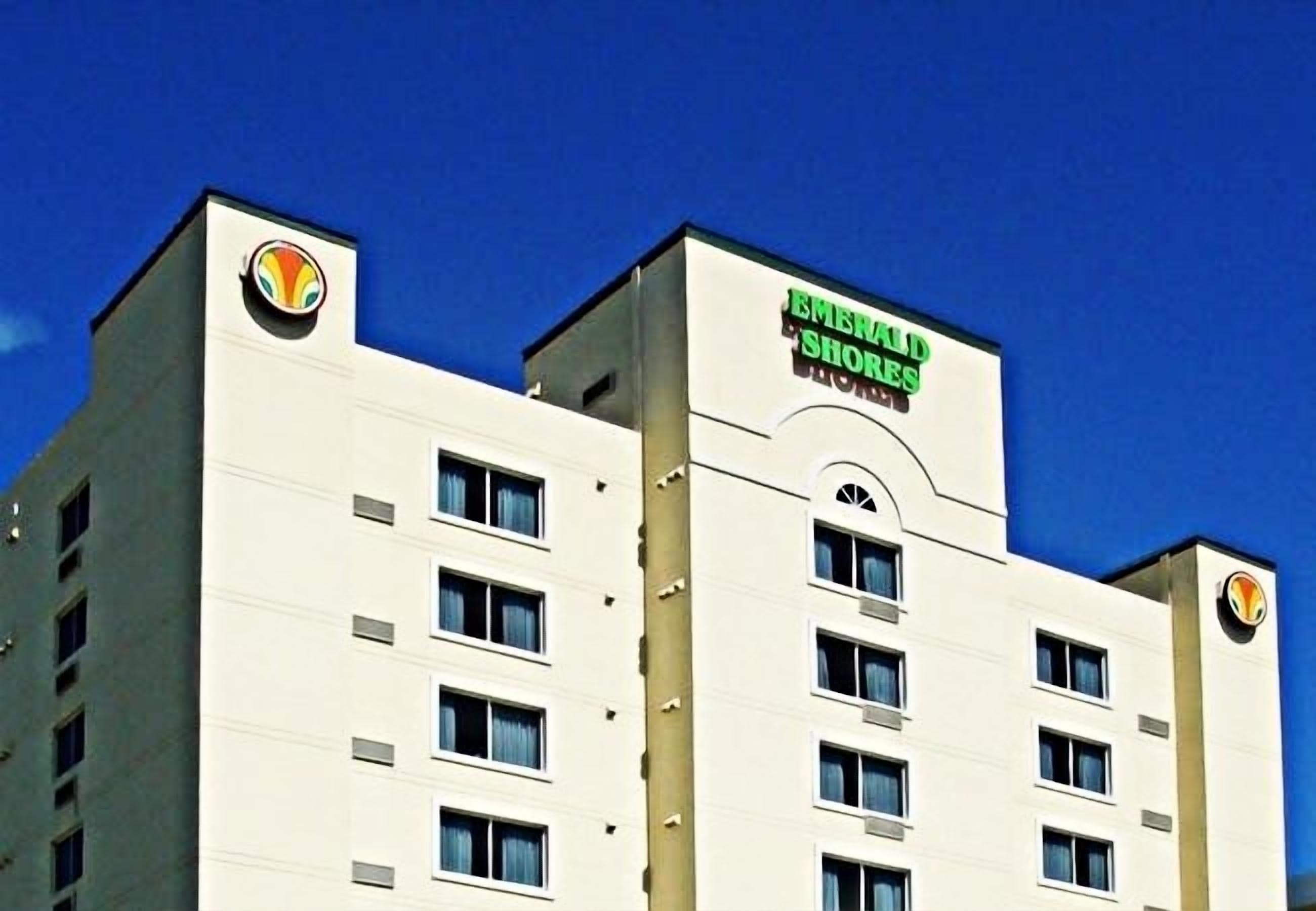 A multi-story hotel with a prominent sign for 'EMERALD SHORES' on the facade.