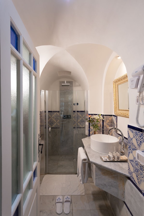 A modern bathroom with a glass-enclosed shower, a white sink, and a vanity with a mirror. - Dar Said (Sidi Bou Said)