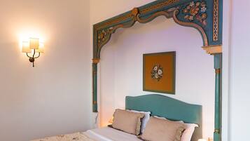 A neatly made bed with floral bedding, a decorative headboard, and a wall-mounted light fixture.